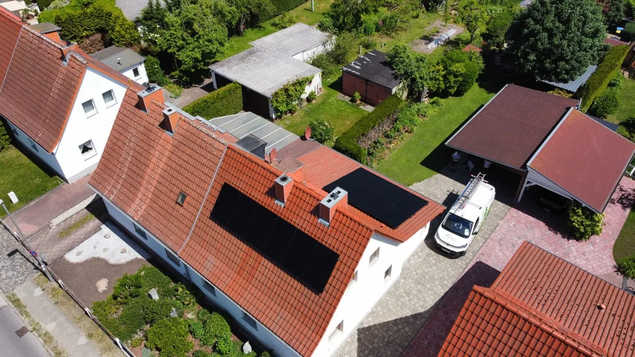 Luftaufnahme verteilter Photovoltaik-Modulflächen auf einem roten Ziegeldach